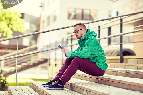 Image of young hipster man with smartphone in city
