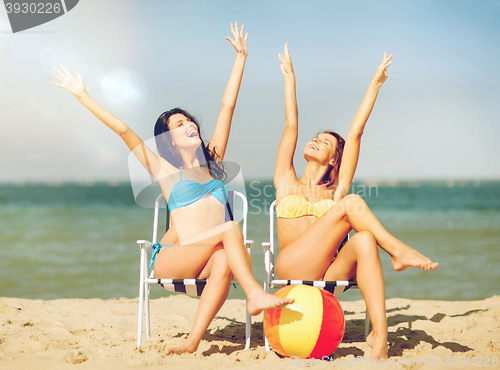 Image of girls sunbathing on the beach chairs