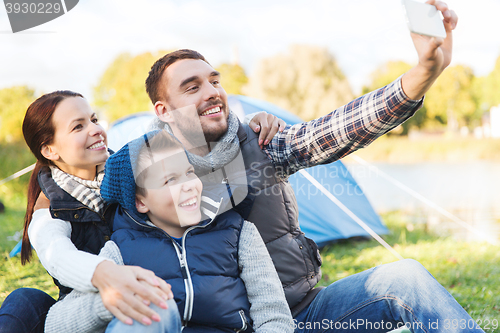 Image of family with smartphone taking selfie at campsite