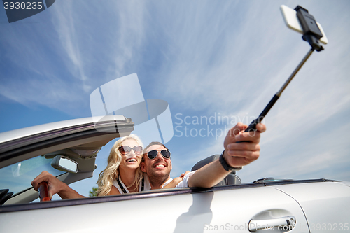 Image of happy couple in car taking selfie with smartphone