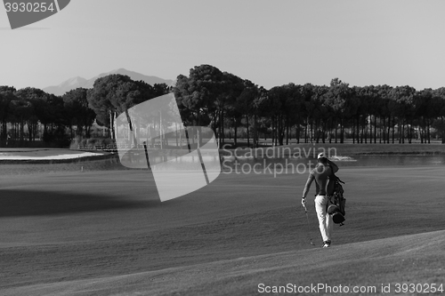 Image of golfer  walking and carrying bag