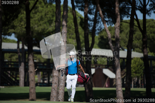 Image of golf player walking and carrying bag