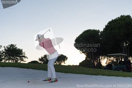 Image of golfer hitting a sand bunker shot on sunset