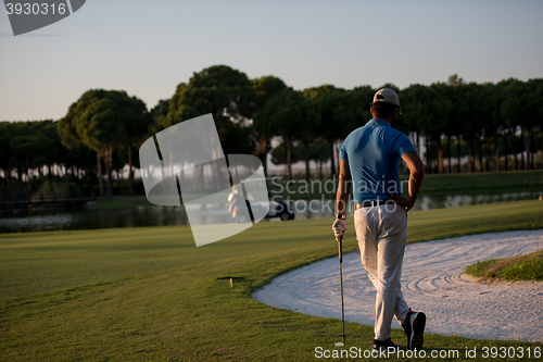 Image of golfer from back at course looking to hole in distance