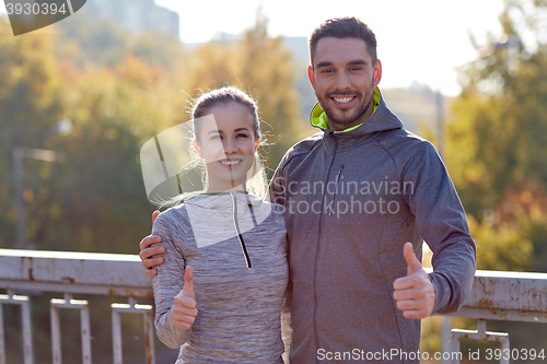 Image of smiling couple showing thumbs up outdoors