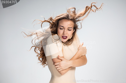 Image of The woman with hair blowing in the wind on gray