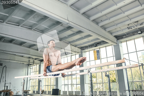 Image of Male gymnast performing handstand on parallel bars