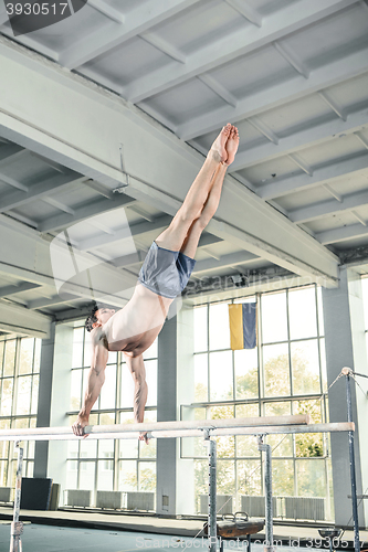 Image of Male gymnast performing handstand on parallel bars