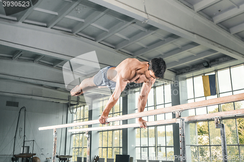 Image of Male gymnast performing handstand on parallel bars