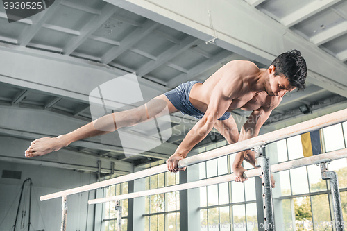 Image of Male gymnast performing handstand on parallel bars