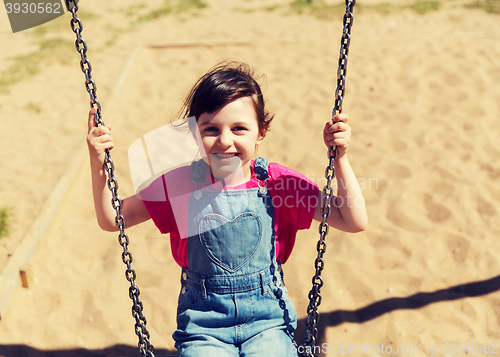 Image of happy little girl swinging on swing at playground