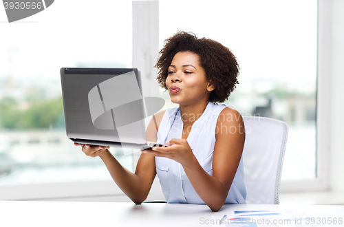 Image of african woman sending kiss to laptop computer