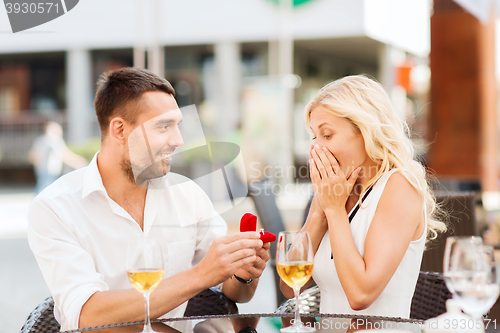 Image of happy couple with engagement ring and wine at cafe