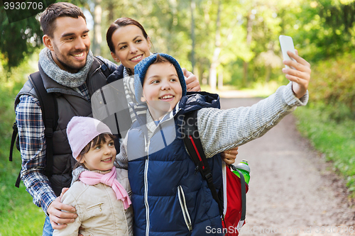 Image of family with backpacks taking selfie by smartphone