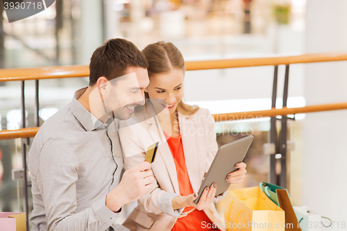 Image of couple with tablet pc and shopping bags in mall