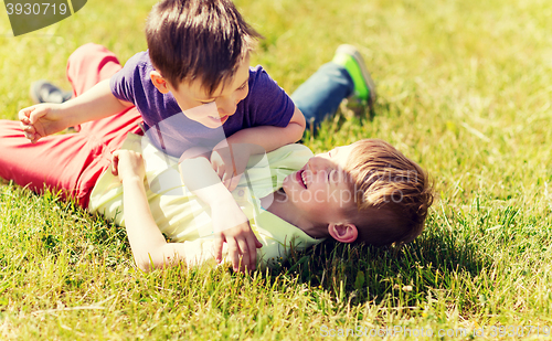 Image of happy little boys fighting for fun on grass