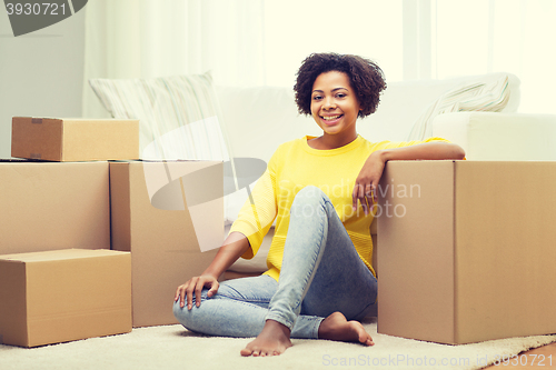 Image of happy african woman with cardboard boxes at home