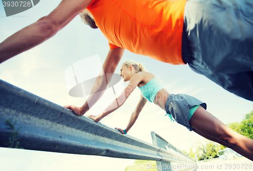 Image of close up of happy couple doing push-ups outdoors