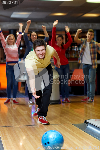 Image of happy young man throwing ball in bowling club