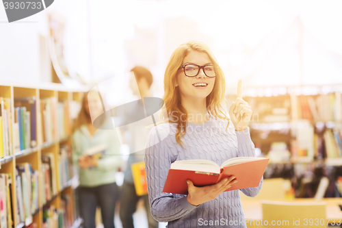 Image of happy student girl or woman with book in library