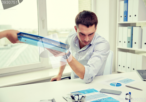 Image of businessman taking papers from secretary in office