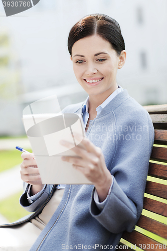 Image of businesswoman reading notes in notepad outdoors