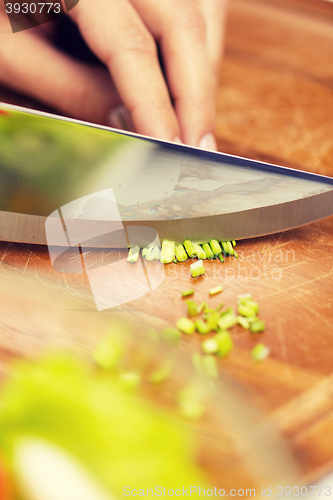 Image of close up of woman chopping green onion with knife