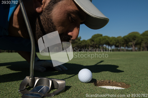 Image of golf player blowing ball in hole