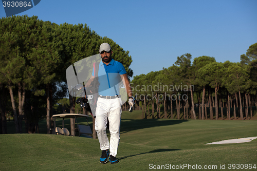 Image of golfer  walking and carrying golf  bag