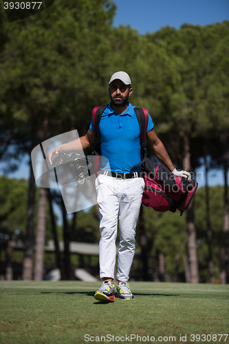 Image of golf player walking and carrying bag