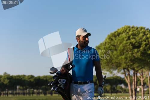 Image of golfer  walking and carrying bag