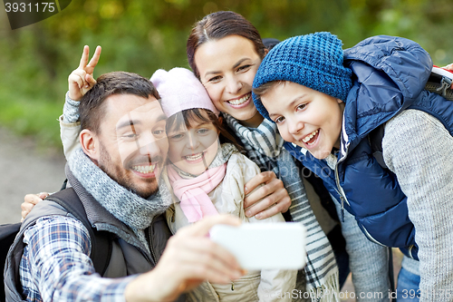 Image of family taking selfie with smartphone in woods