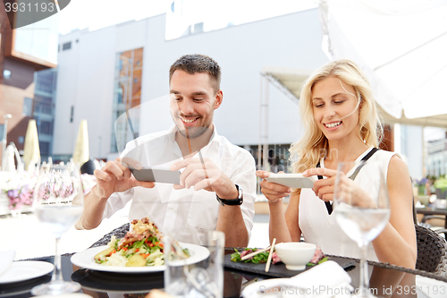 Image of happy couple with smatphone photographing food