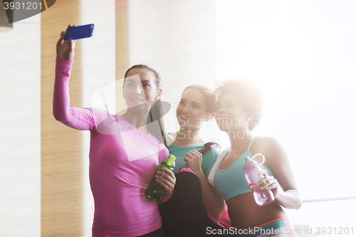 Image of happy women with smartphone taking selfie in gym