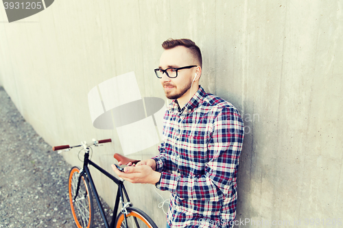 Image of hipster man in earphones with smartphone and bike