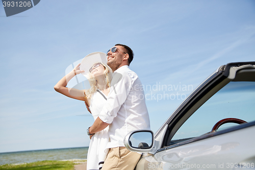 Image of happy couple hugging near cabriolet car at sea