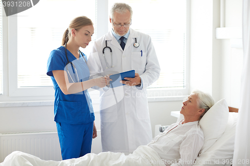 Image of doctor and nurse visiting senior woman at hospital