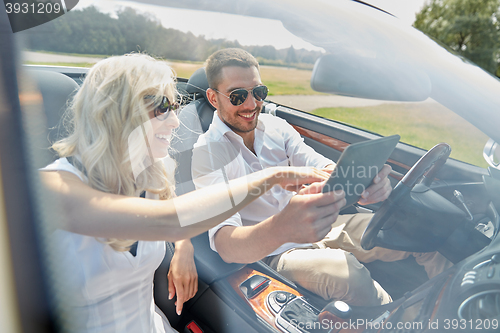 Image of happy couple with tablet pc in cabriolet car