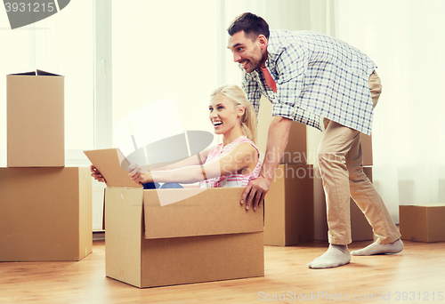 Image of couple with cardboard boxes having fun at new home