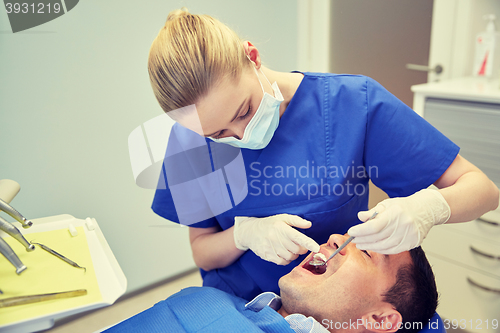 Image of female dentist checking up male patient teeth