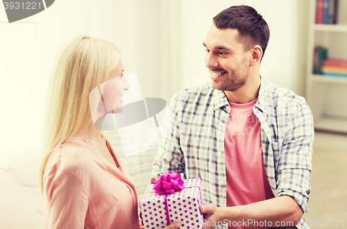 Image of happy man giving woman gift box at home