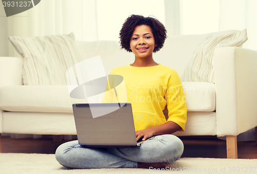 Image of happy african american woman with laptop at home