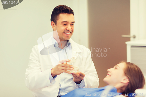 Image of happy dentist showing jaw layout to patient girl