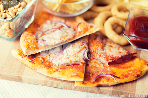 Image of close up of pizza and other snacks on wooden table