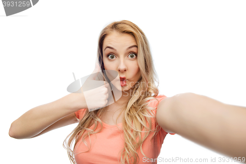 Image of young woman taking selfie and showing thumbs up