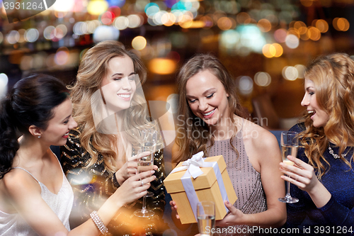 Image of happy women with champagne and gift at night club