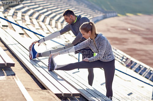 Image of couple stretching leg on stands of stadium