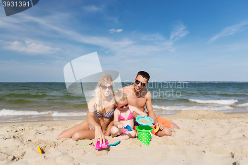 Image of happy family playing with sand toys on beach