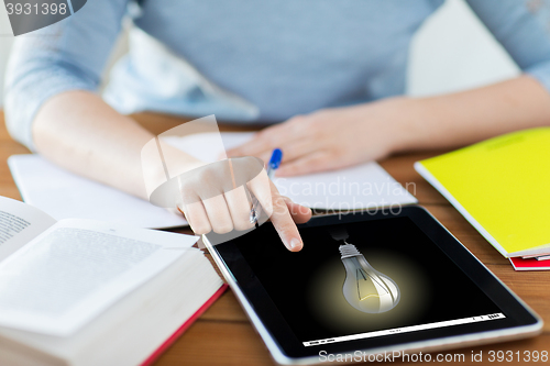 Image of close up of student with light bulb on tablet pc