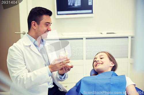 Image of happy dentist showing jaw layout to patient girl